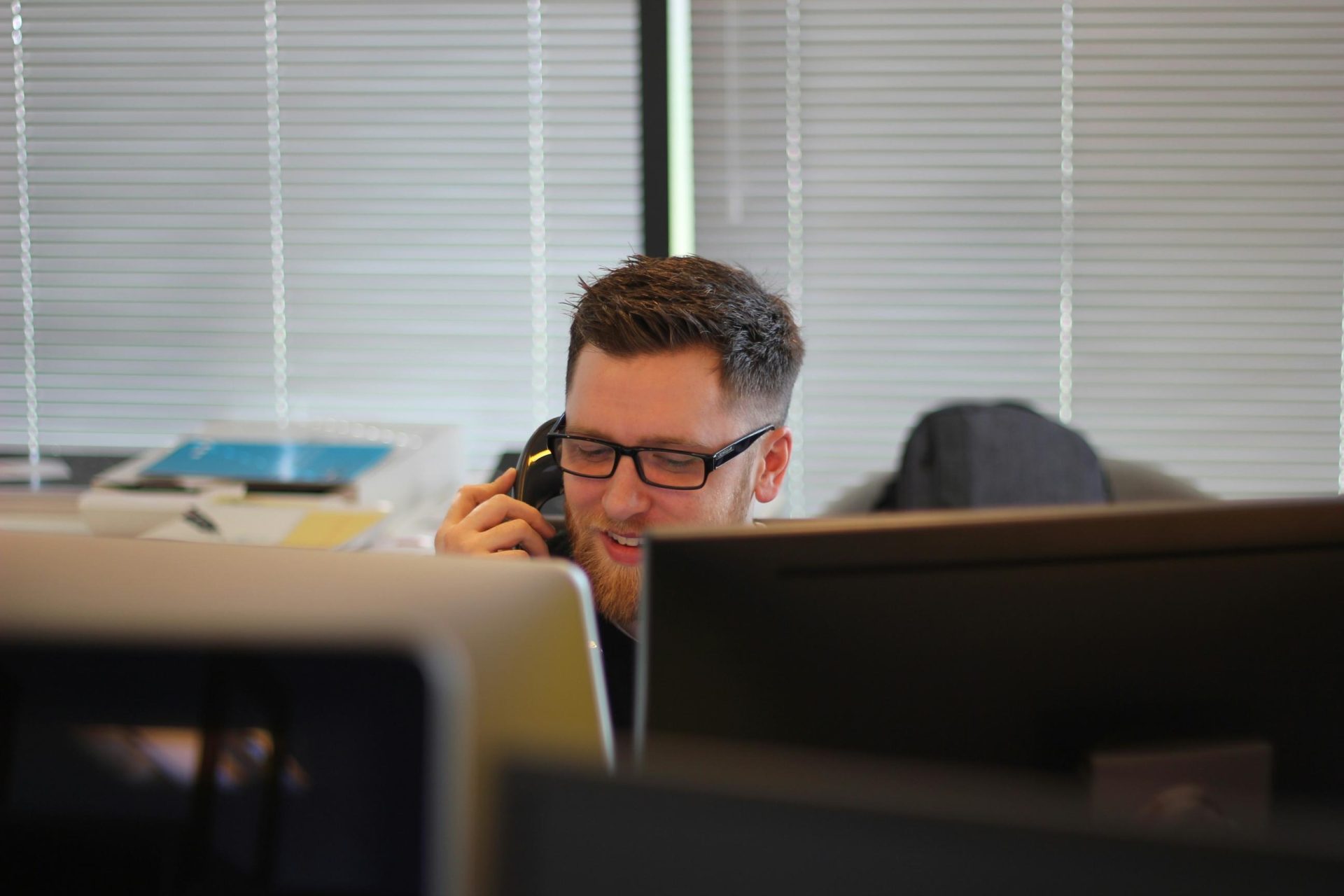 Man talking on the phone with laptops in front of him